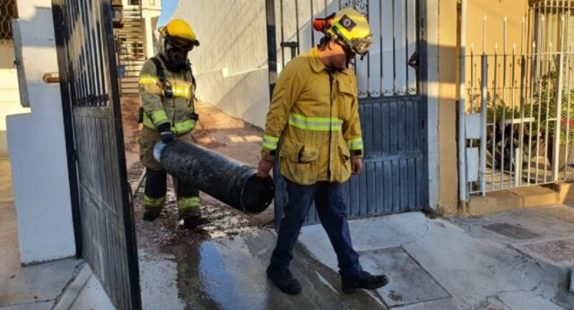 Elementos de Bomberos de Guaymas cargan el cilindro de gas, tras el incendio en una casa de la calle 21 y avenida 18.